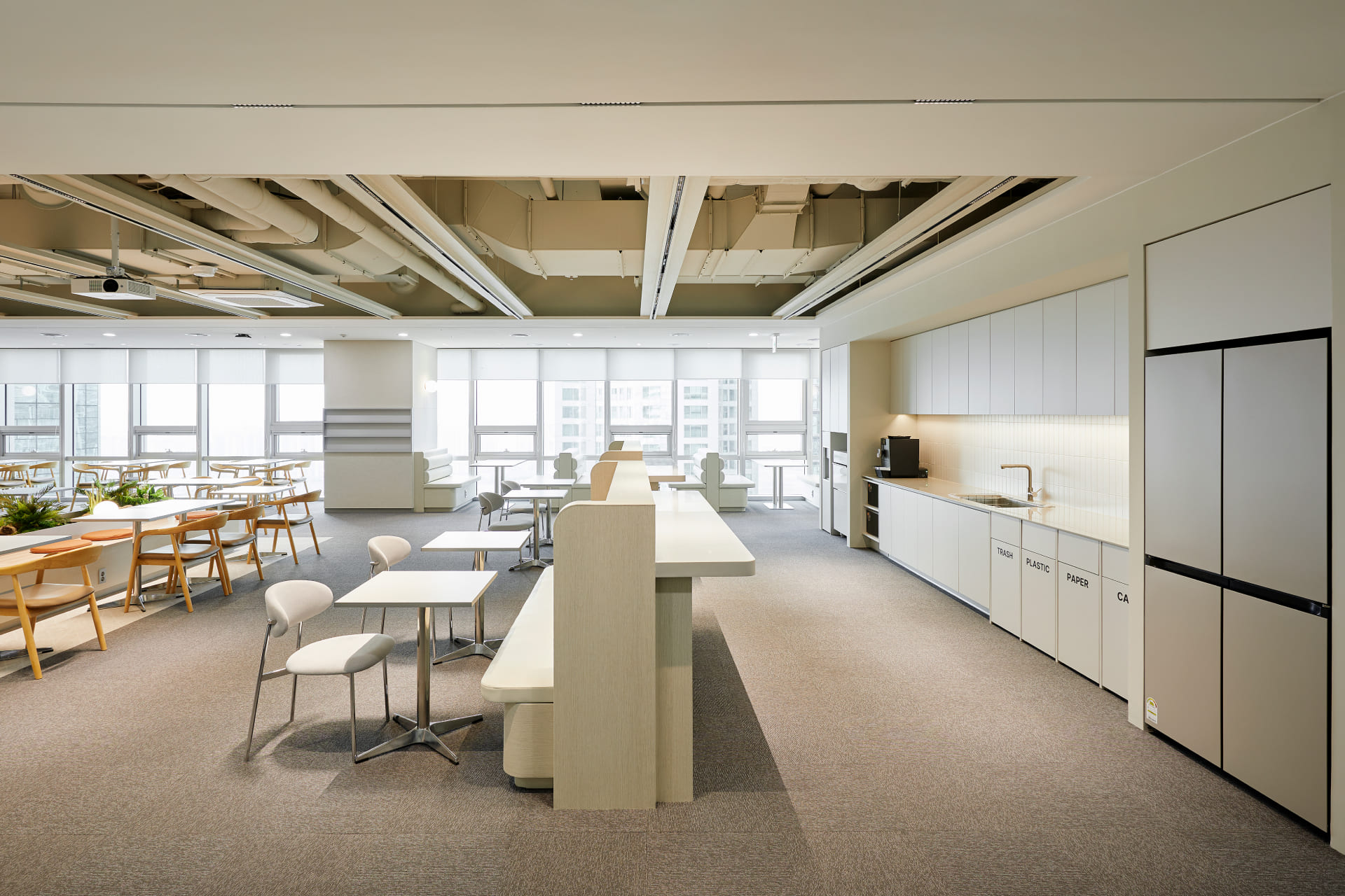 화이트 톤의 깔끔한 주방 가구와 쓰레기 분리수거함이 빌트인된 모던한 사옥 카페테리아 및 라운지.jpg