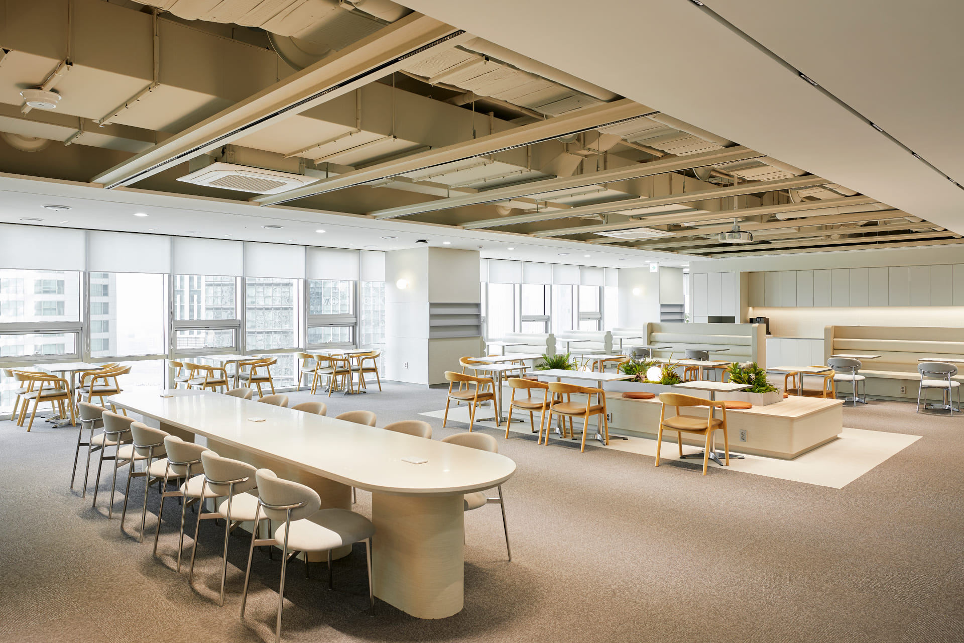 다인원 회의가 가능한 긴 원형 테이블과 플랜테리어 벤치가 설치된 오픈형 협업 라운지.jpg