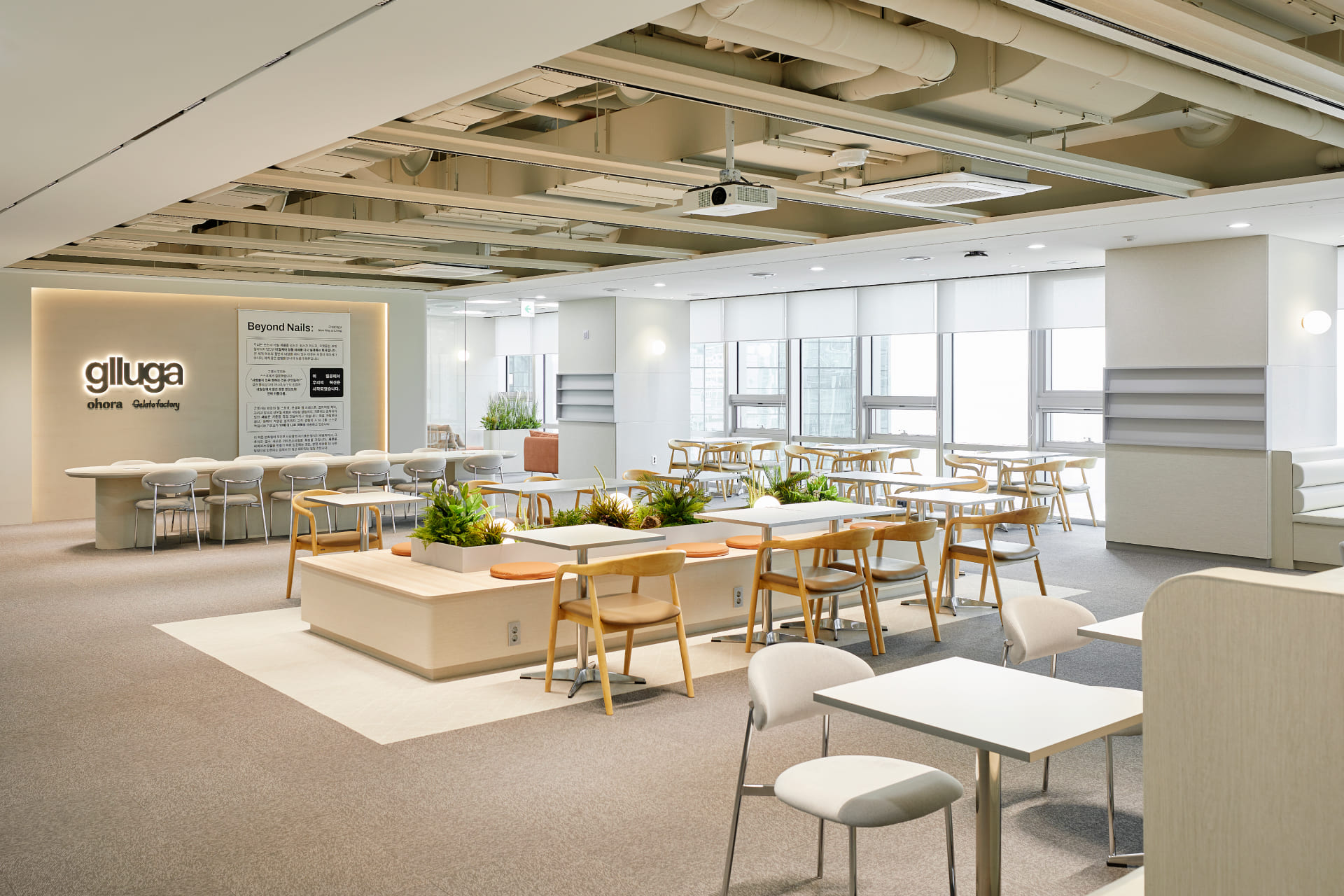 글루가 로고가 부착된 벽면과 내추럴 우드 톤 가구로 꾸며진 세련된 사옥 카페테리아.jpg
