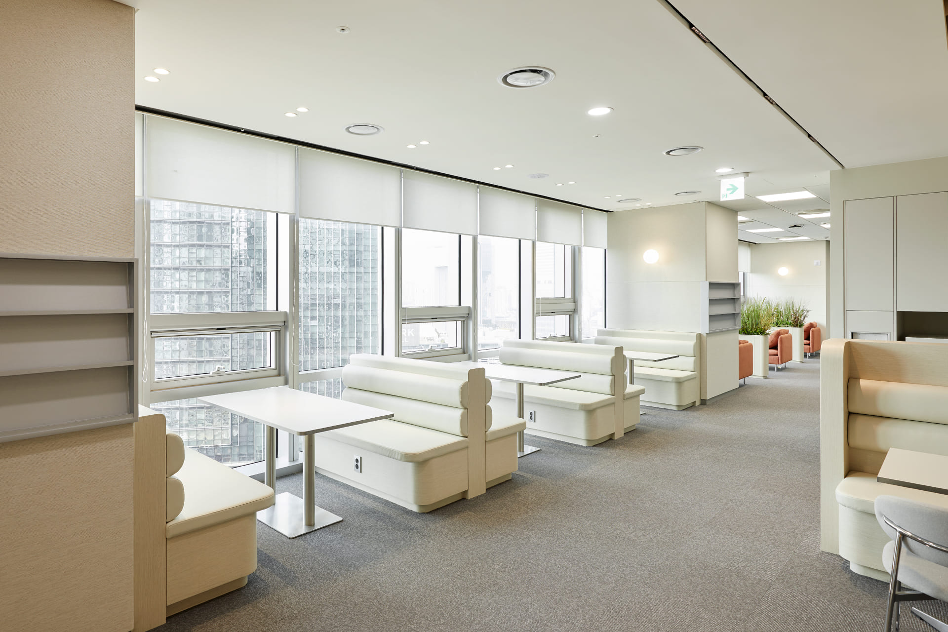창가에 배치된 화이트 가죽 소재의 부스형 소파와 깔끔한 미팅용 테이블.jpg