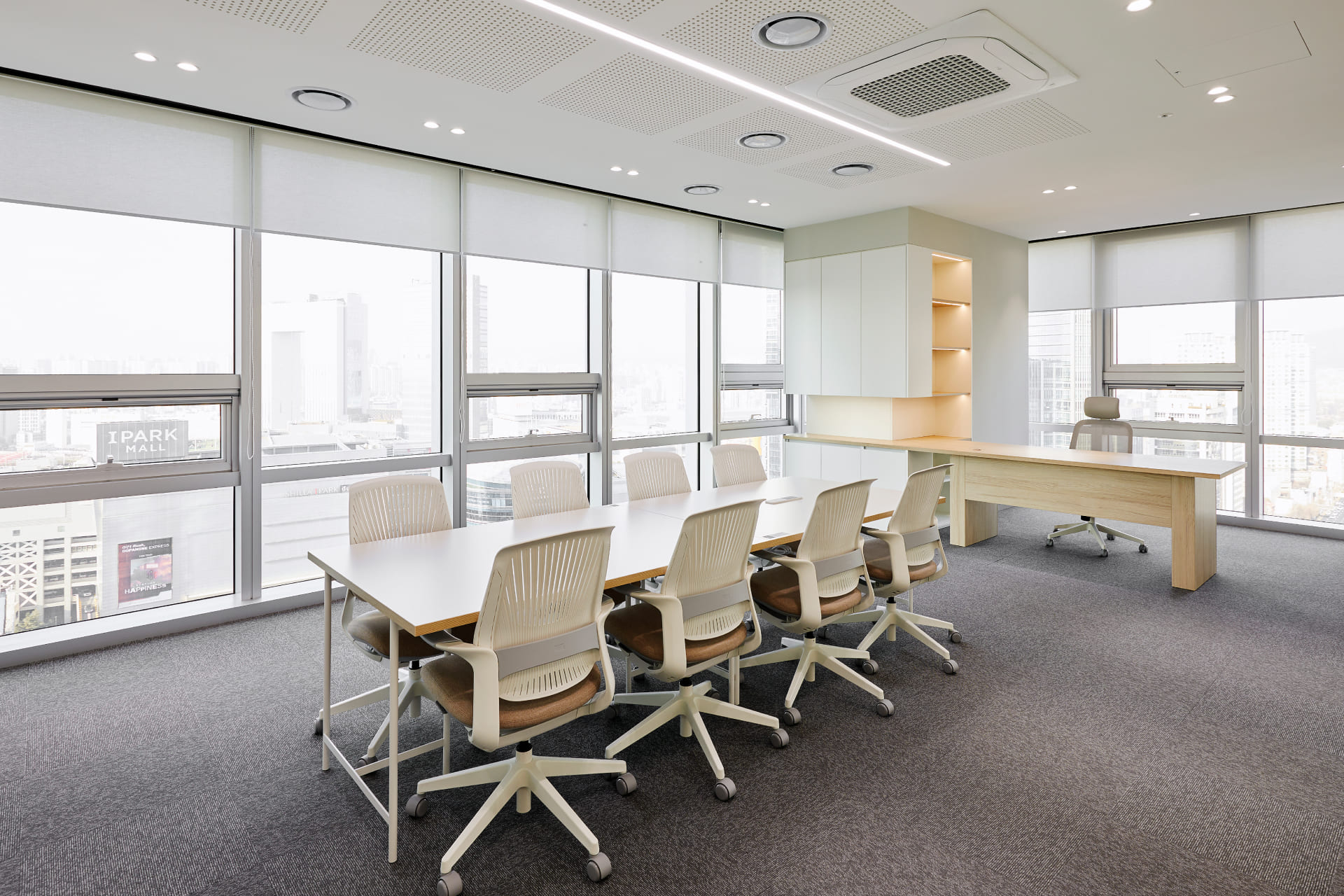 도심 전망이 한눈에 들어오는 넓은 통창과 우드 데스크가 배치된 고급스러운 미팅 공간.jpg