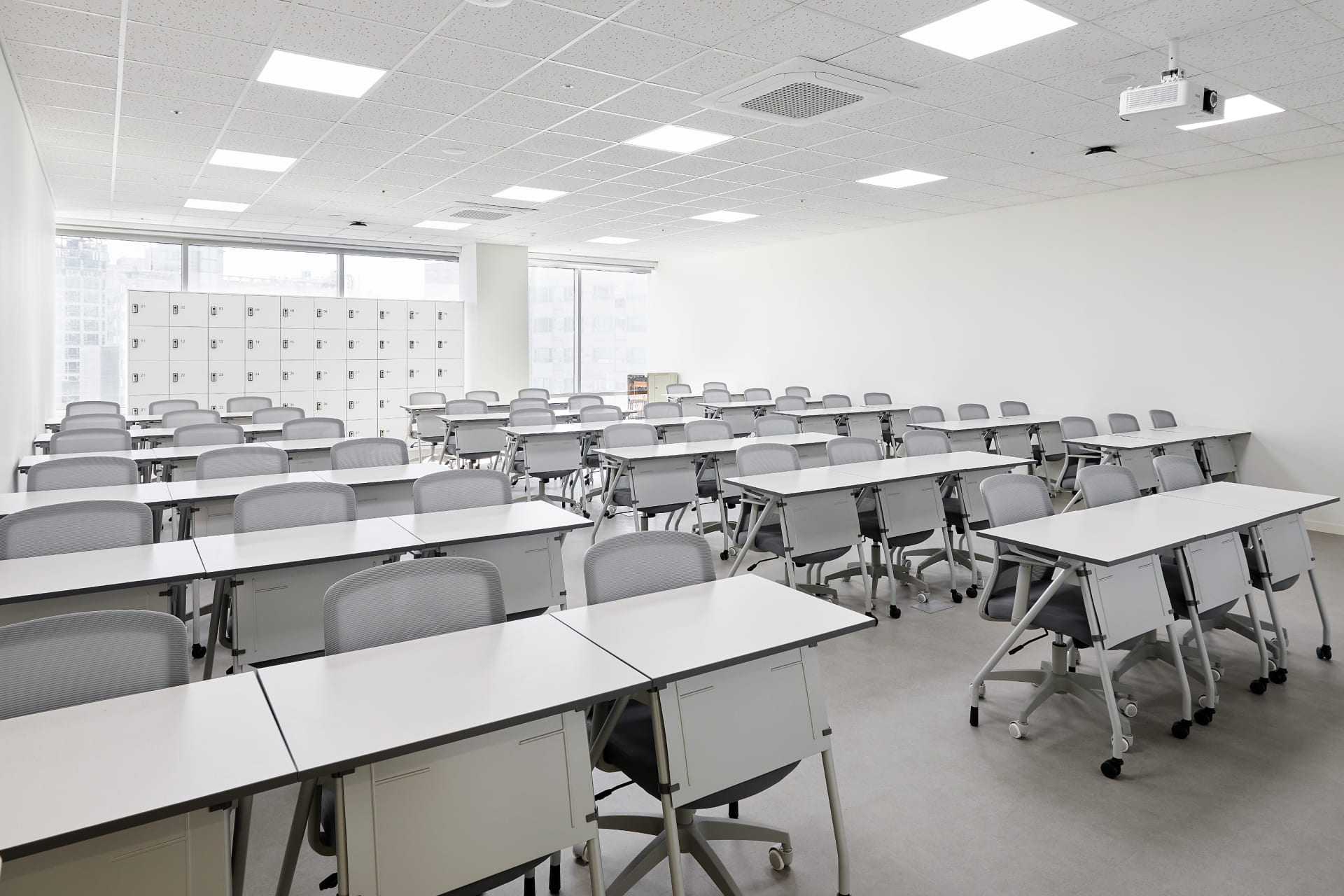 집중 학습을 위한 넓은 화이트 데스크와 인체공학적 메쉬 의자가 배치된 현대적인 강의실 내부.jpg