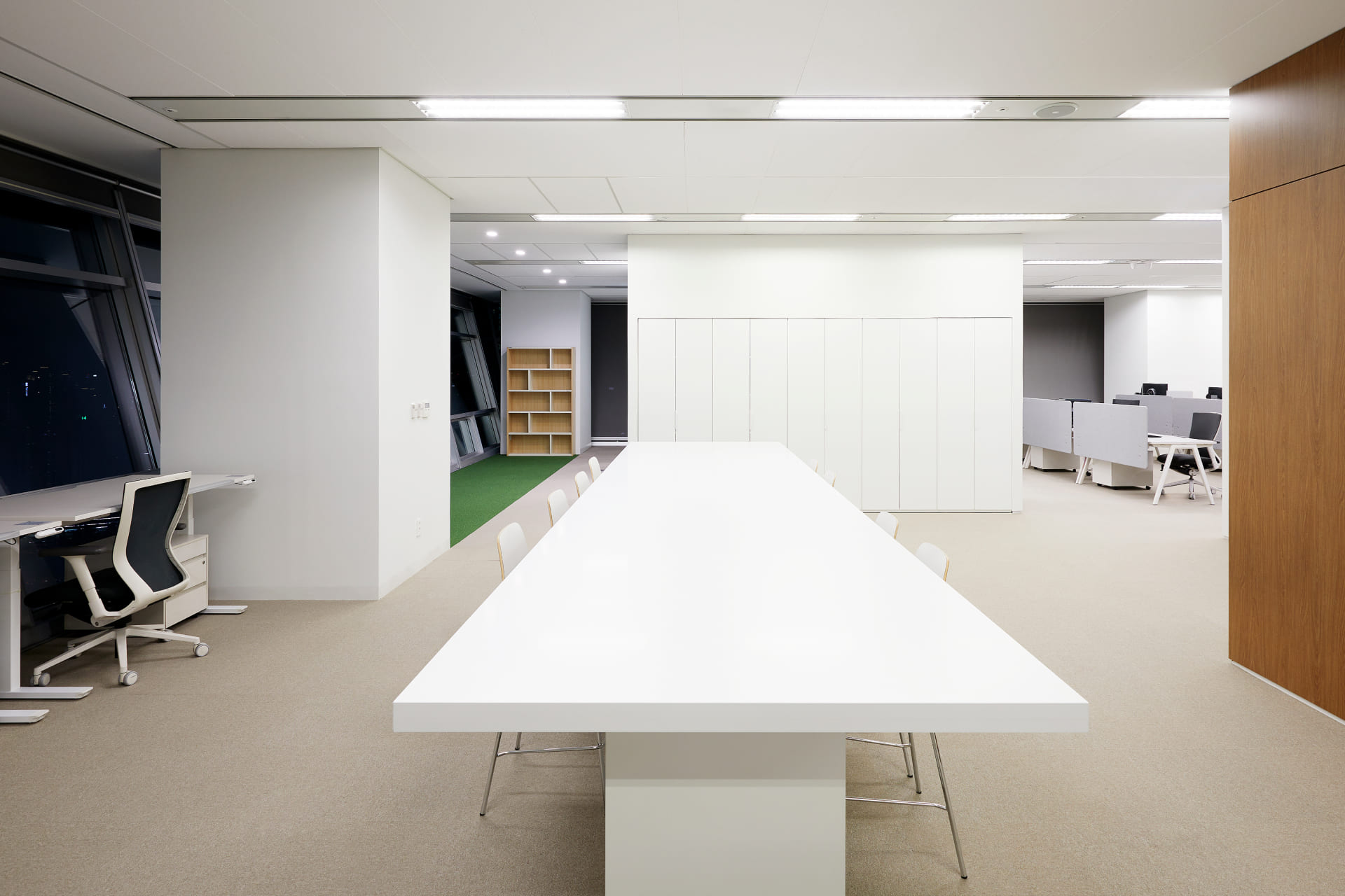 협업을 위한 긴 화이트 대형 테이블과 화사한 조명이 조화로운 모던한 스타일의 오피스 공용 라운지.jpg
