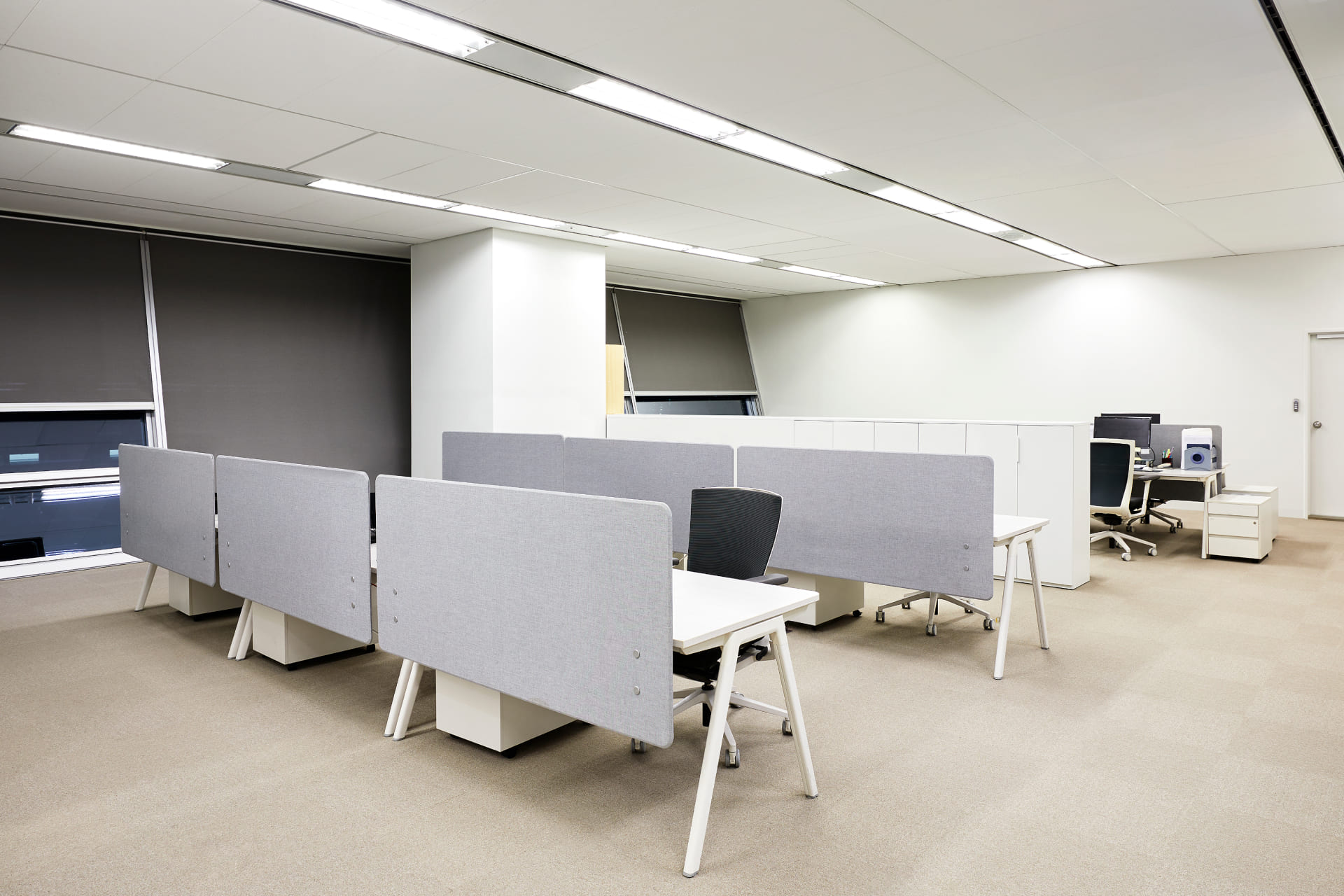 그레이 톤의 파티션과 인체공학적 의자가 배치된 집중도를 높여주는 화이트 톤의 개방형 사무실 업무 공간.jpg