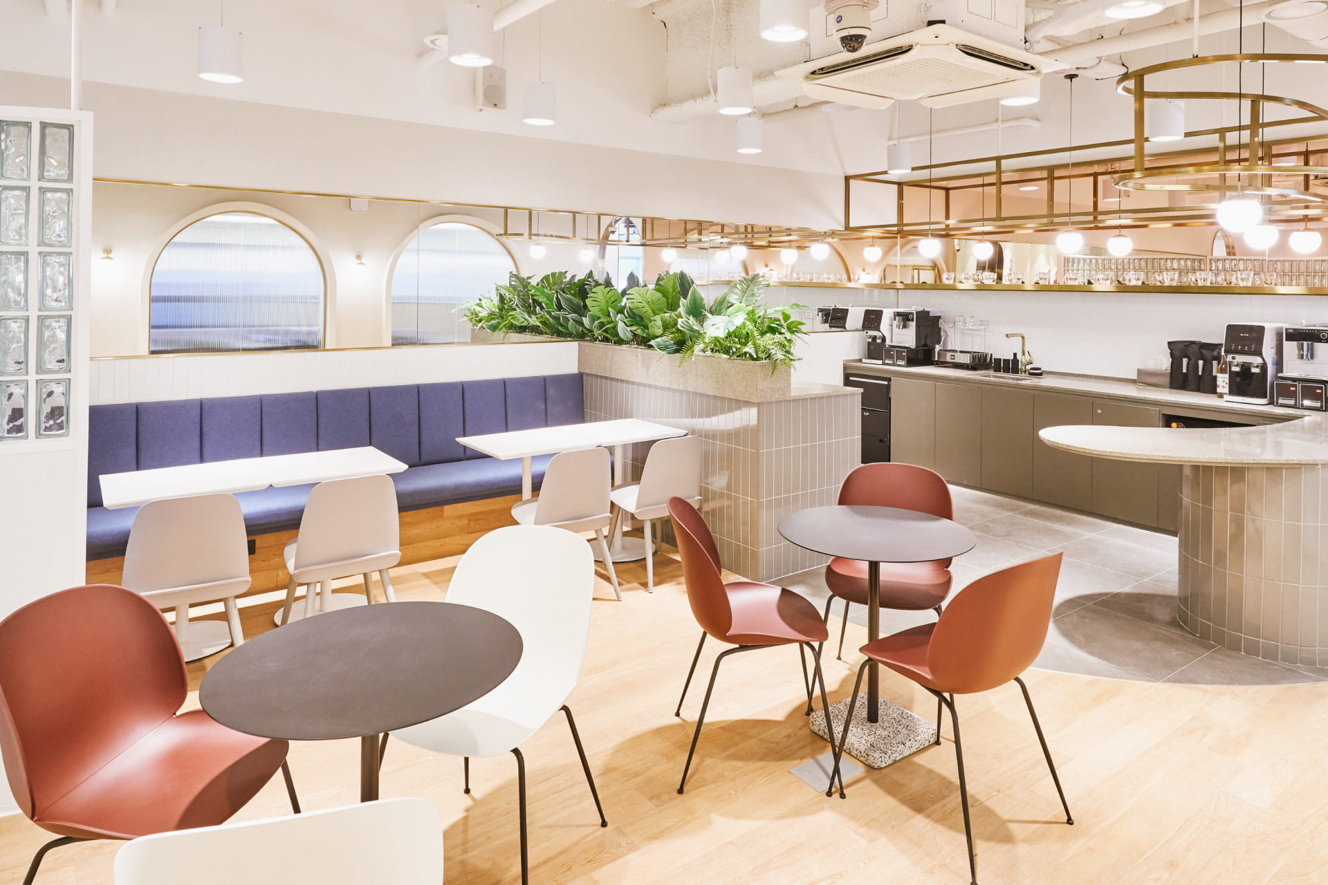 아치형 창문과 플랜테리어가 조화를 이룬 패스트파이브 라운지 내 바 테이블과 파스텔 톤 가구 구성.jpg