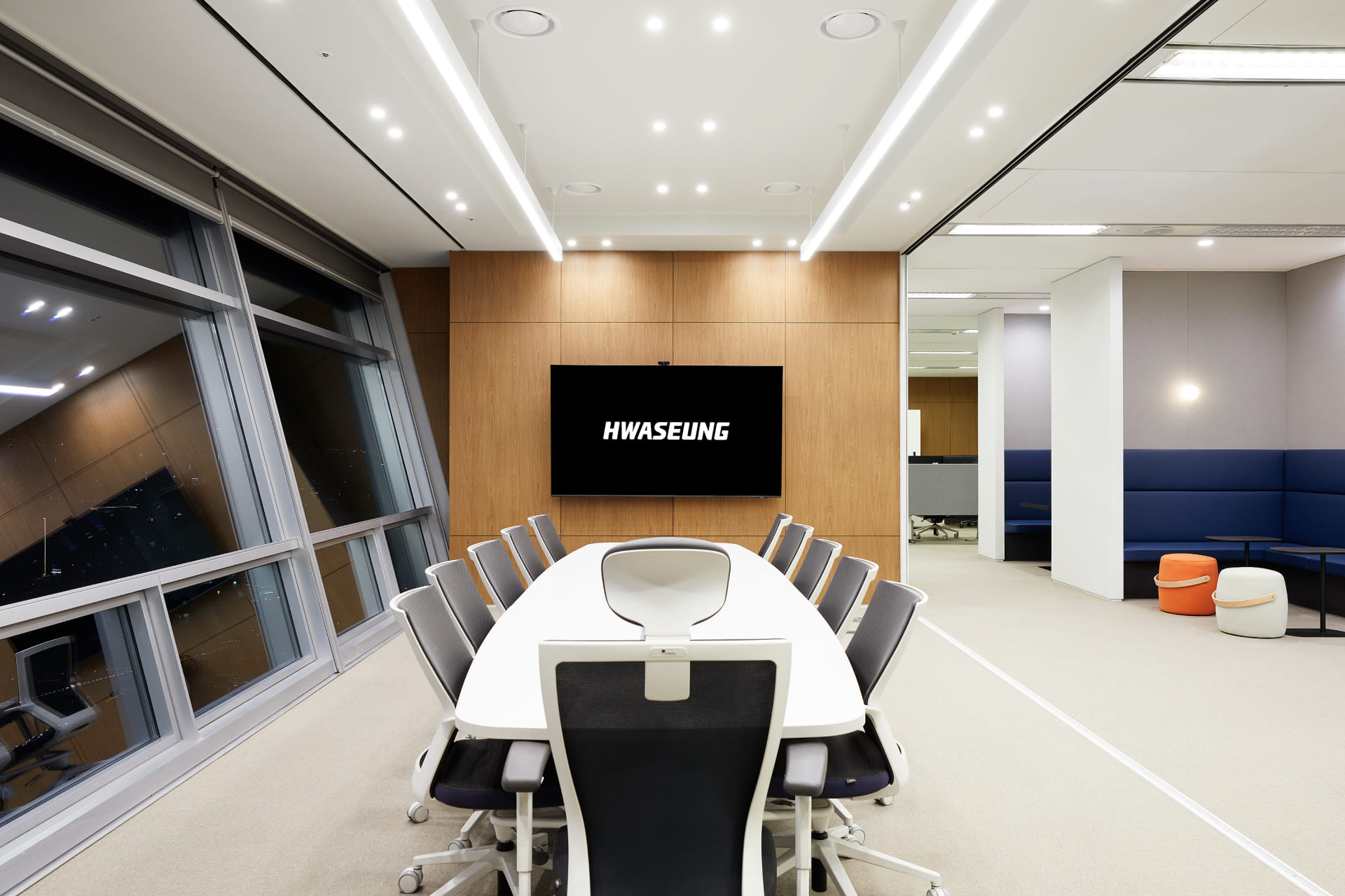 우드 월 포인트와 긴 화이트 테이블이 설치된 대회의실 내부 및 측면에 배치된 블루 톤의 휴게용 소파 좌석.jpg