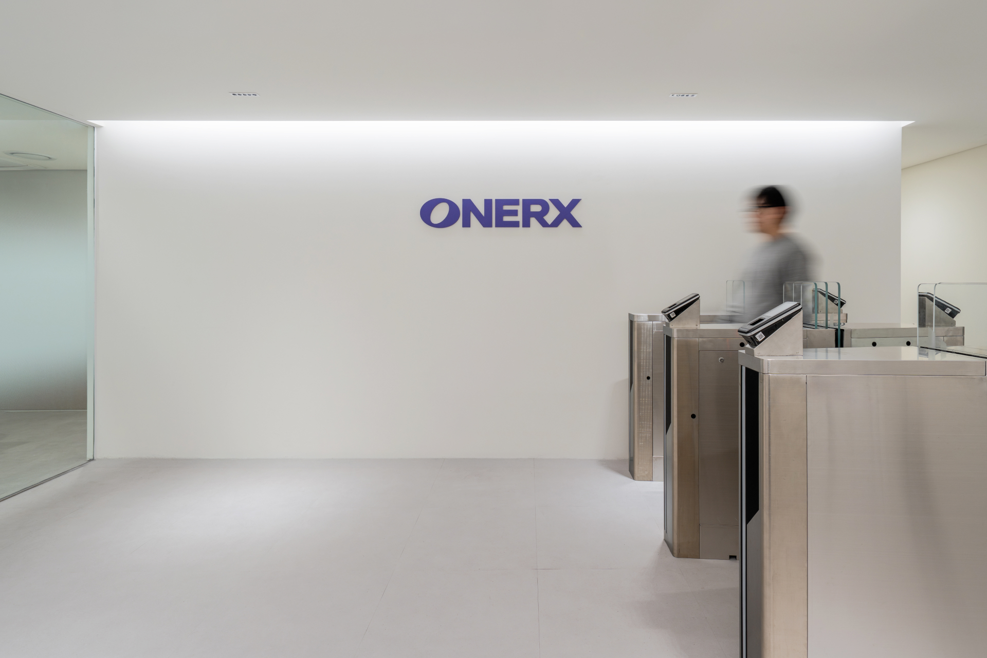 ONERX 로고가 부착된 화이트 벽면과 보안을 위한 스테인리스 스틸 스피드게이트가 설치된 기업 입구.jpg