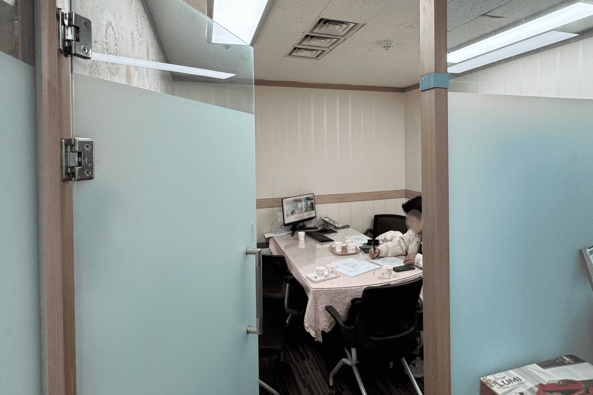 지에이코리아 사무실 인테리어 리모델링 전, 반투명 유리문 안쪽에 테이블보 덮인 테이블이 놓인 좁고 낡은 기존 회의실.png