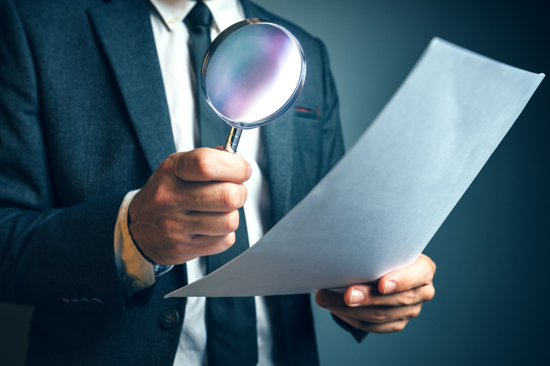 정장을 입은 담당자가 돋보기를 들고 인테리어 견적서 및 계약 서류의 세부 항목을 정밀 검토하는 모습.jpg